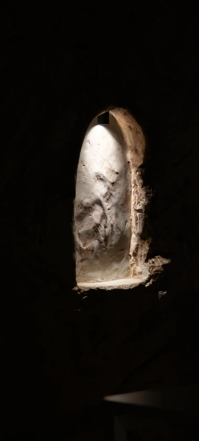 A sculpted lit niche carved into the dark wall of the cathedra