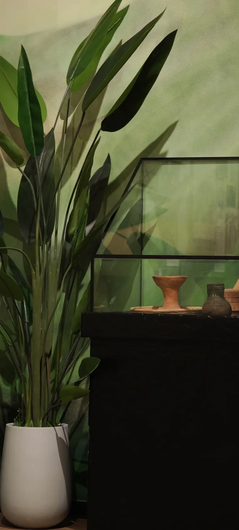 Ethiopian pottery in a glass case against the painted green landscape